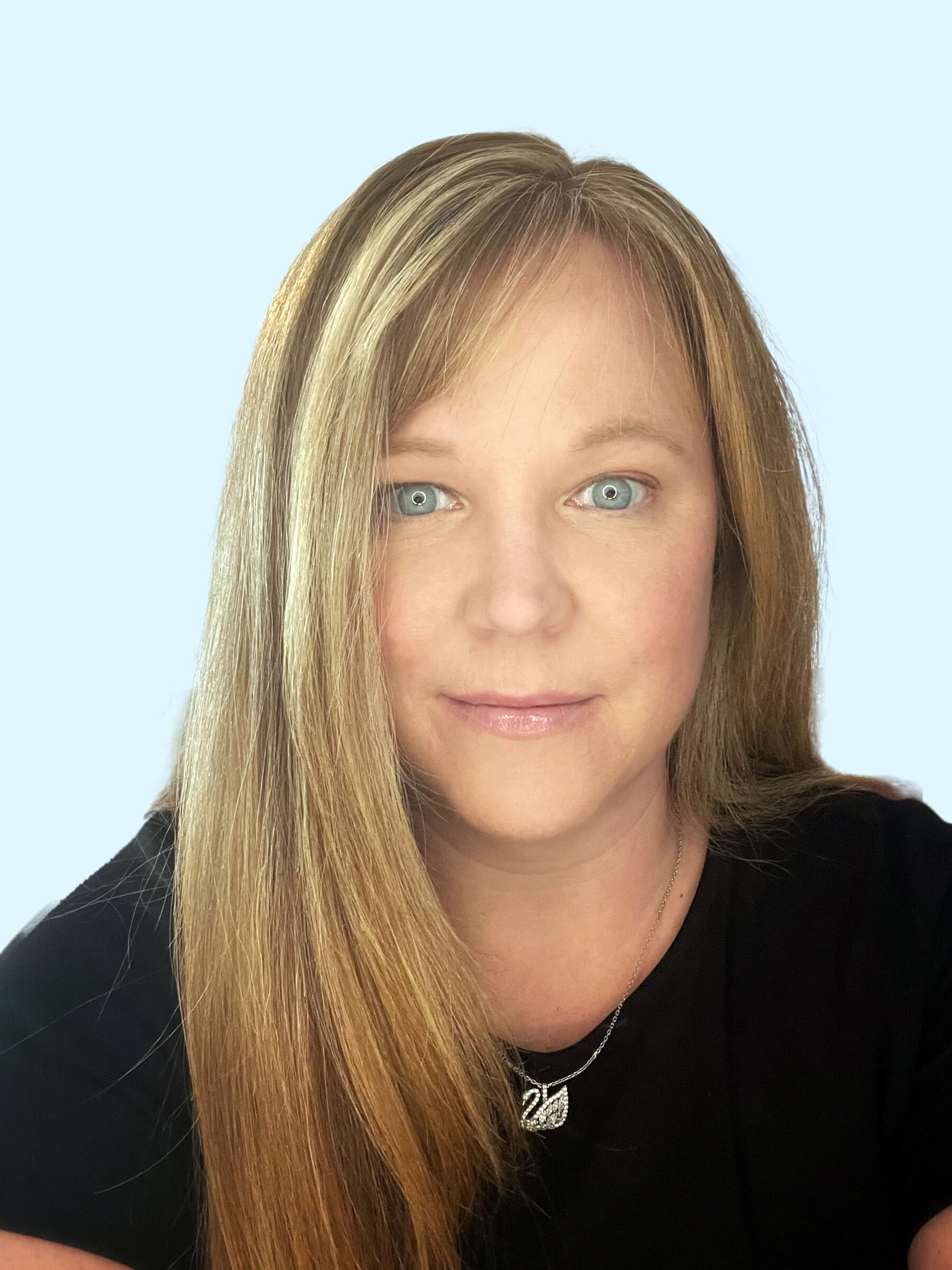 Photo of Dr. Kara Patterson from the shoulders up. She has long straight strawberry blonde hair and blue eyes. She is wearing a black t-shirt and has a necklace with a swan on it. She is smiling.